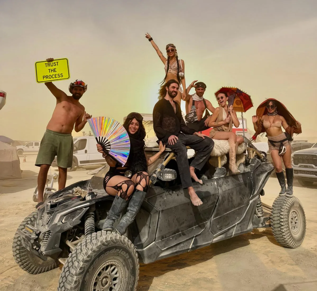 Camp UBU's art car on the playa at Burning Man, crowded with campers, with a Trust the Process sign