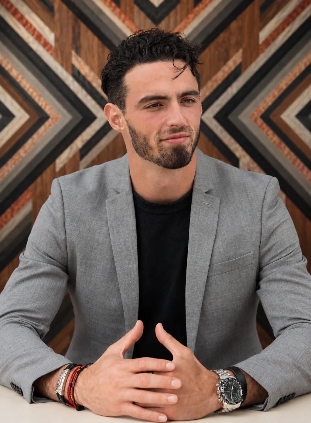 Kodah Pipitone in a grey blazer at a table in front of a chevron wood wall